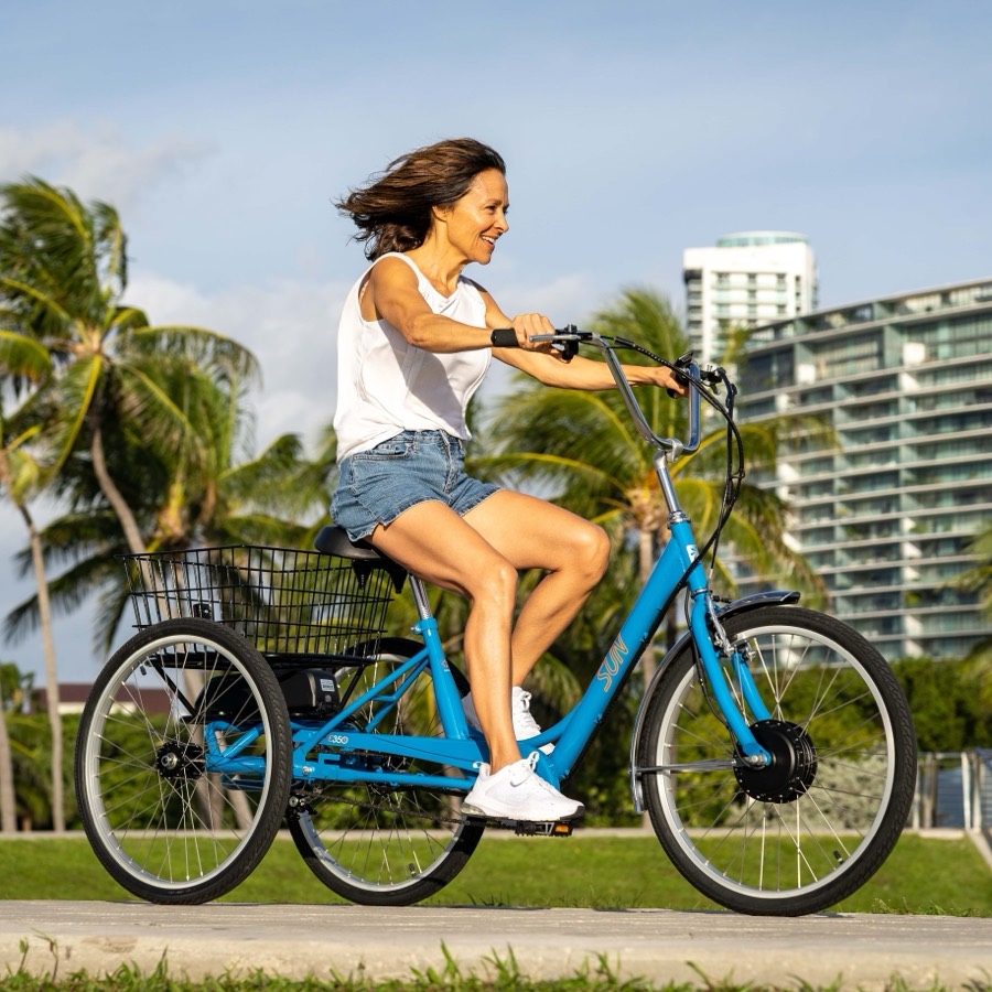 A rider on a blue Sun Bicycles E350 electric trike on a palm-lined Miami Beach path.