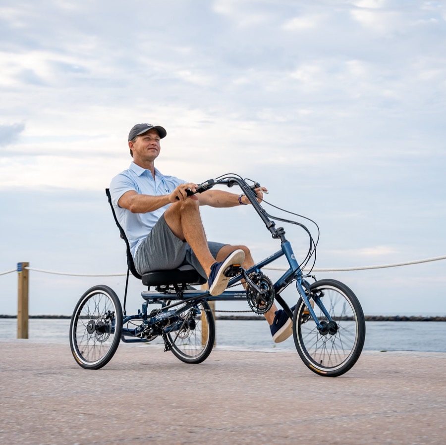 A rider on a blue Sun Seeker recumbent trike on a seawall path at South Beach.
